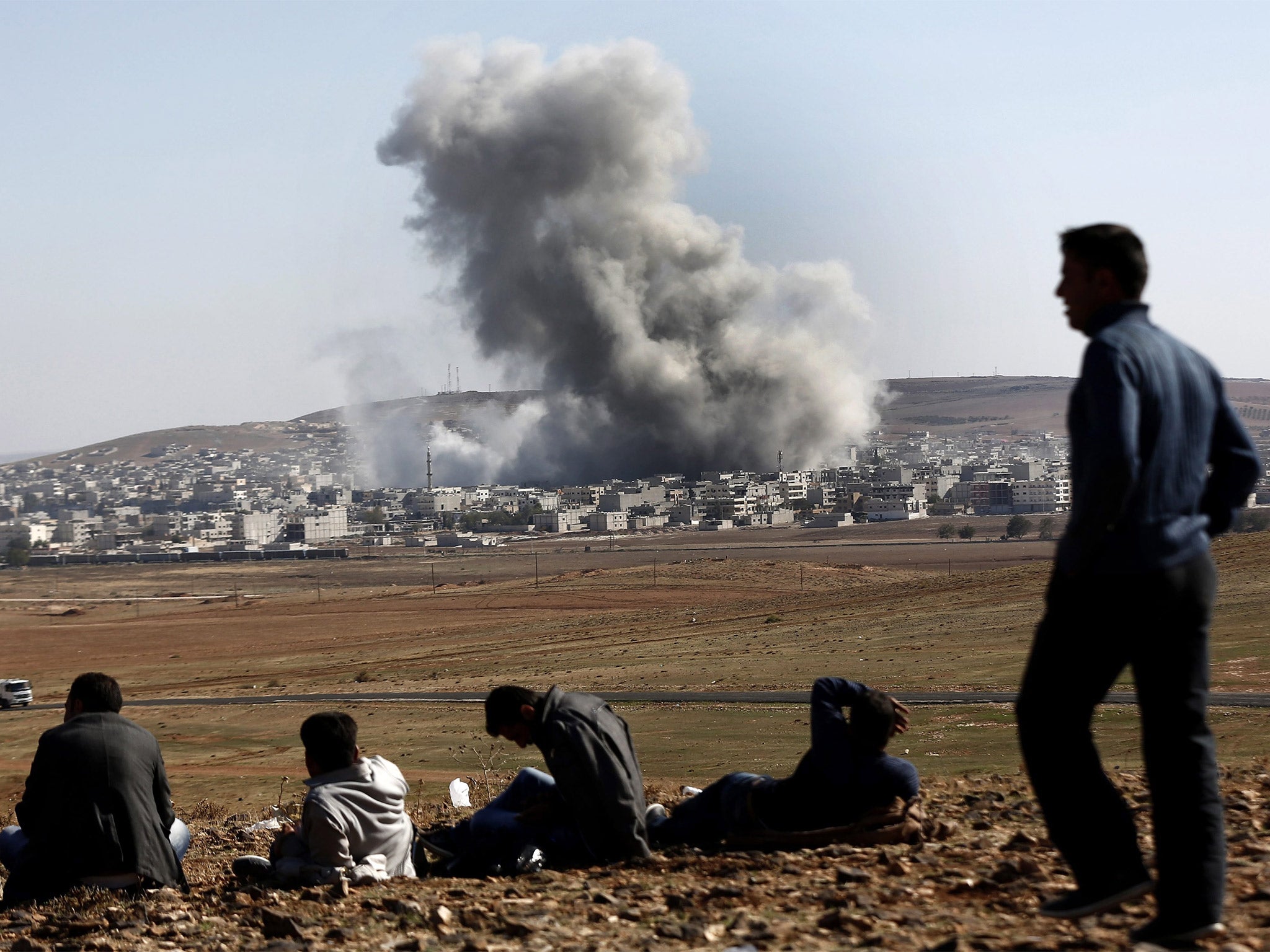 People watch an explosion after an apparent US-led coalition air strike on Kobani, Syria