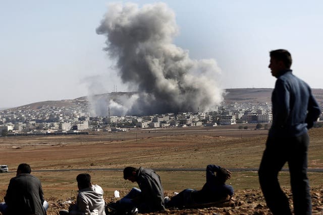 People watch an explosion after an apparent US-led coalition airstrike on Kobani, Syria