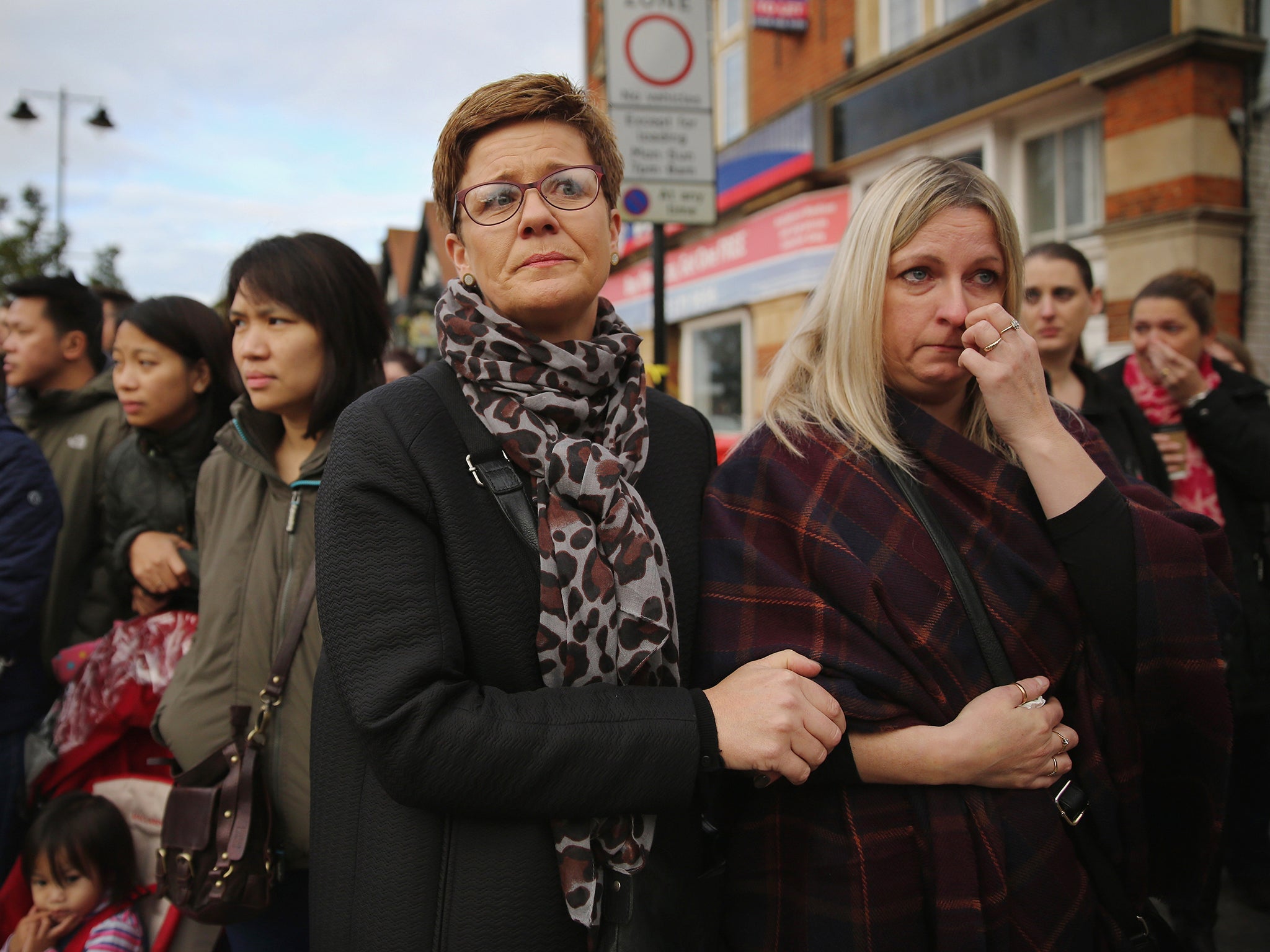 Members of the community watch as the funeral cortege for murdered teenager Alice Gross passes through Hanwell town in London