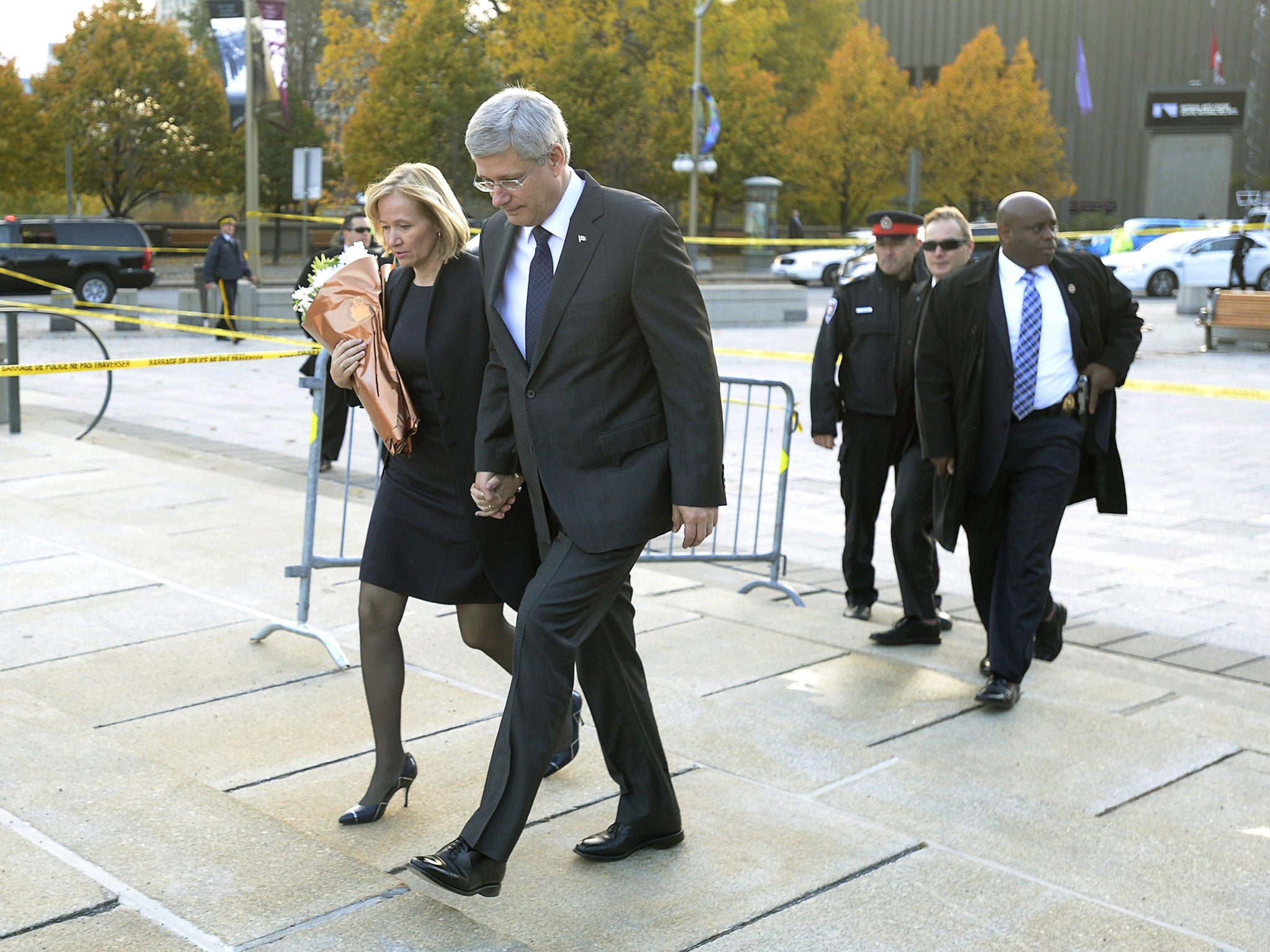 Prime Minister Stephen Harper and his wife Laureen walk up to the perimeter of the National Memorial to lay flowers in Ottawa on Thursday, October 23