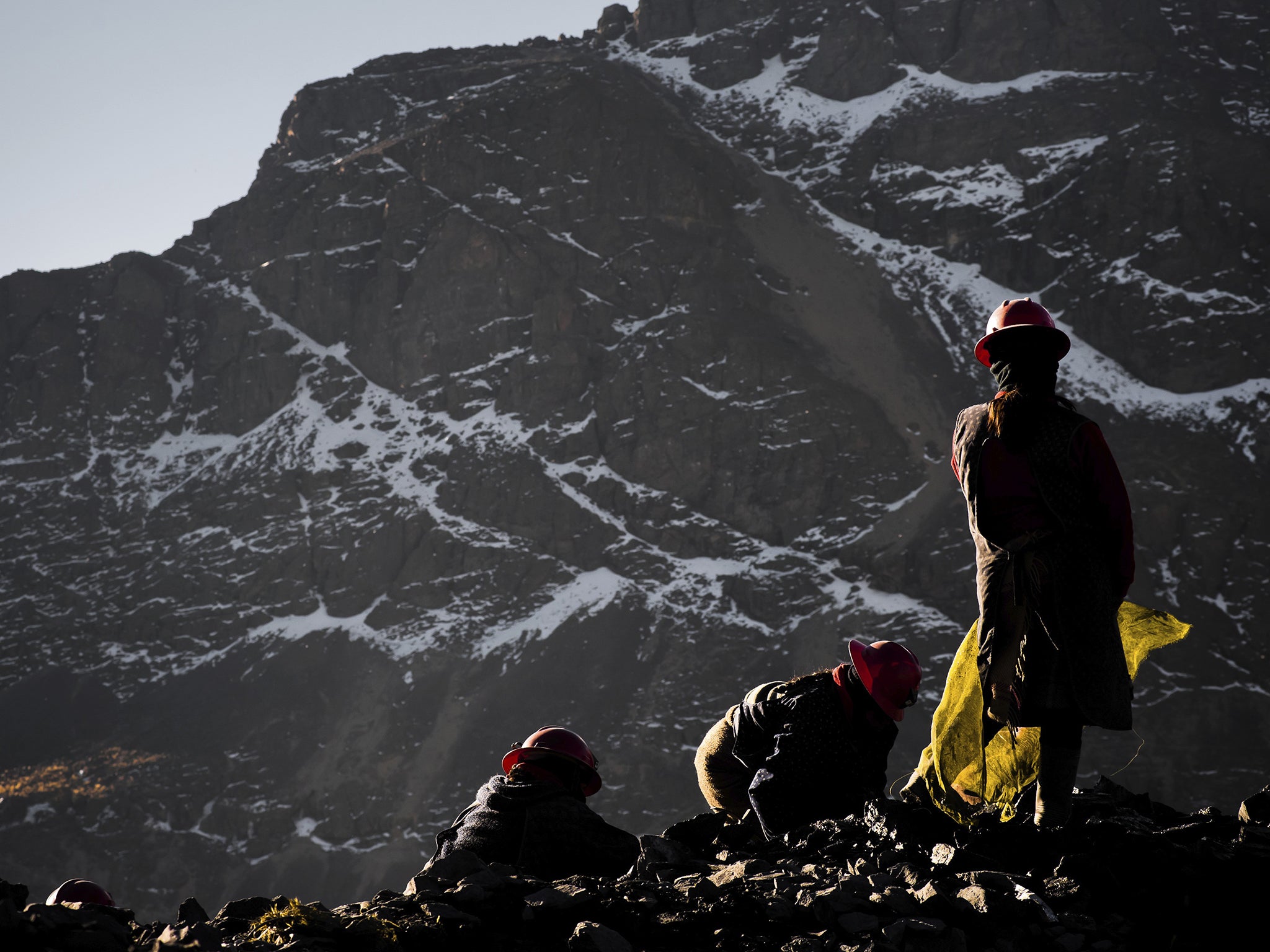 Women miners search for gold on waste rock from mines in La Rinconada, Peru