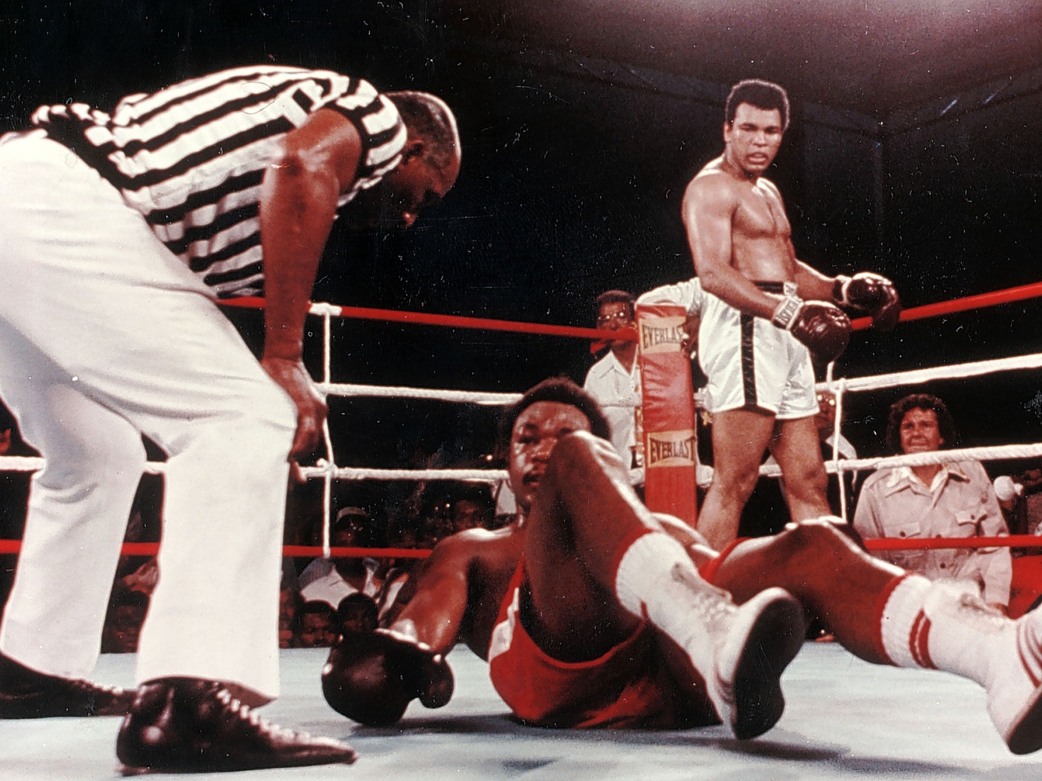 Muhammad Ali floors George Foreman in the Rumble in the Jungle, with Gene Kilroy (in safari jacket, right) watching ringside