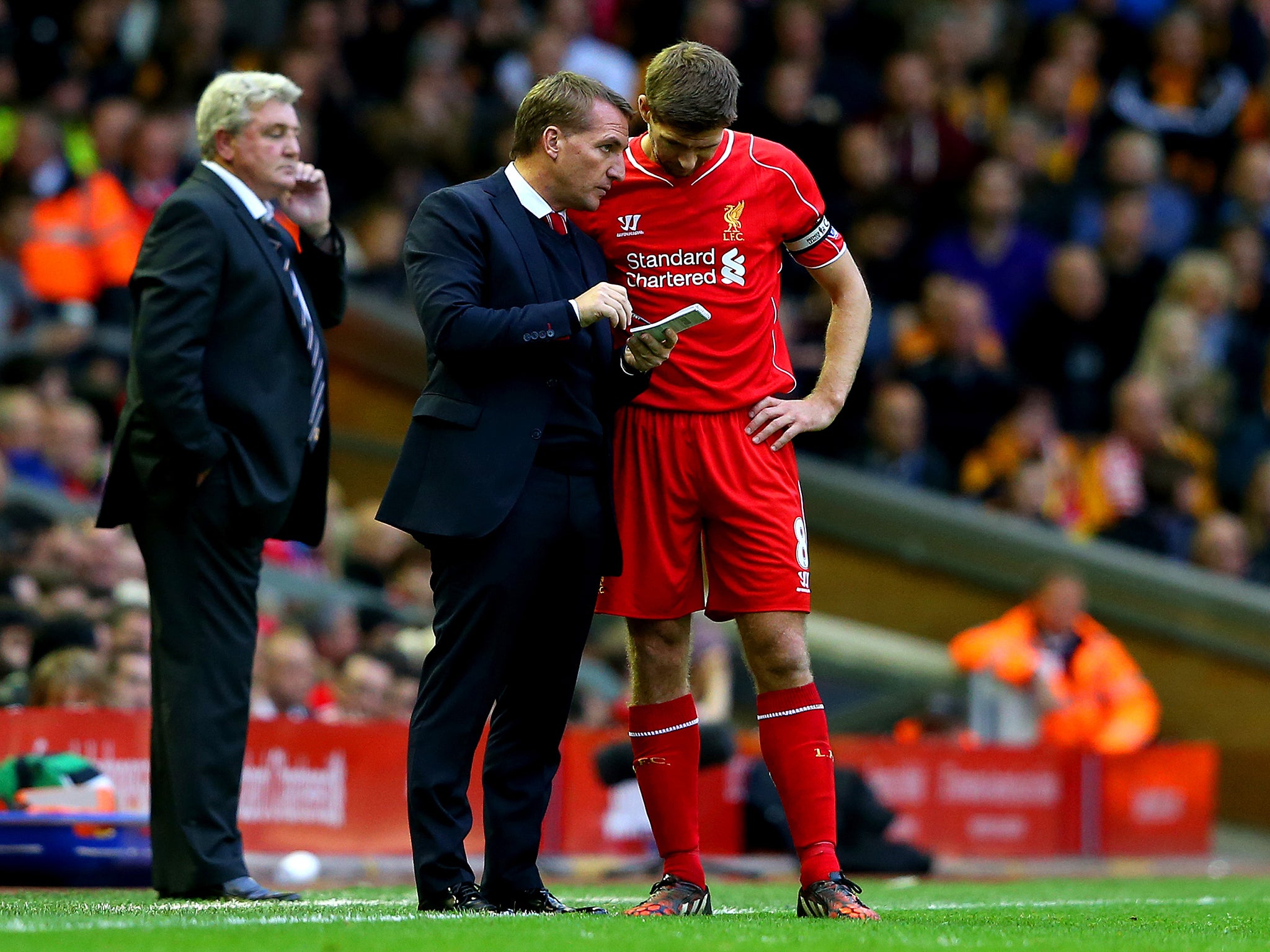 Brendan Rodgers, manager of Liverpool speaks with his captain Steven Gerrard as Steve Bruce manager of Hull City looks on