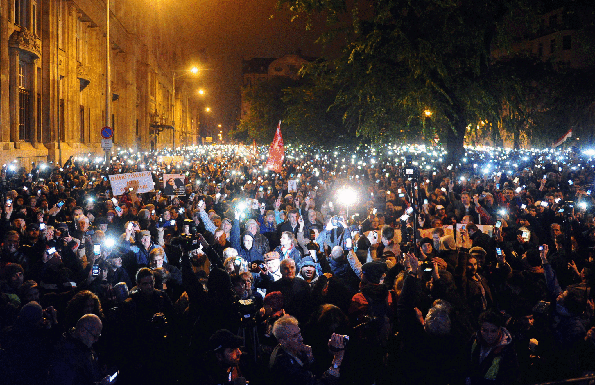 Hungarian citizens lift their mobile phones to protest against the goverment's new tax plan for the introduction of the internet tax next year in Budapest
