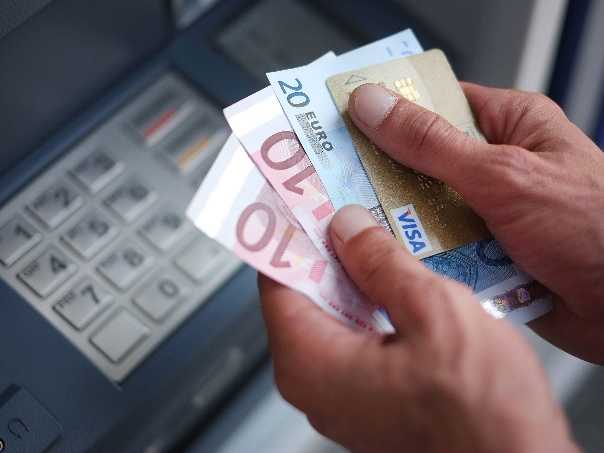 A man takes out Euro banknotes from an automated teller machine (ATM) at a cash point of the French bank 'La Banque Postale' in Carquefou, Western France.