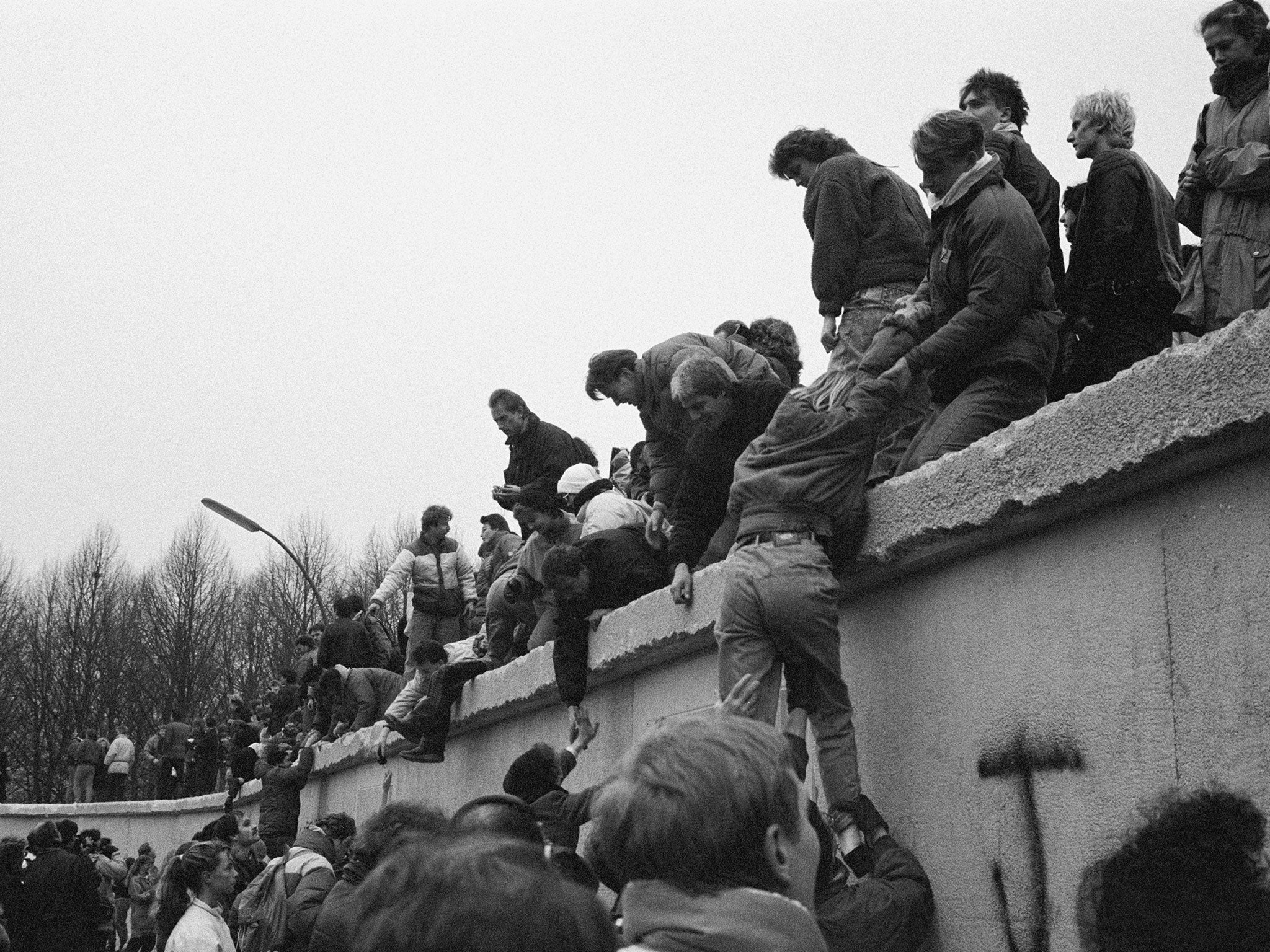 East Berliners climb onto the Berlin Wall to celebrate the effective end of the city's partition on 31st December 1989