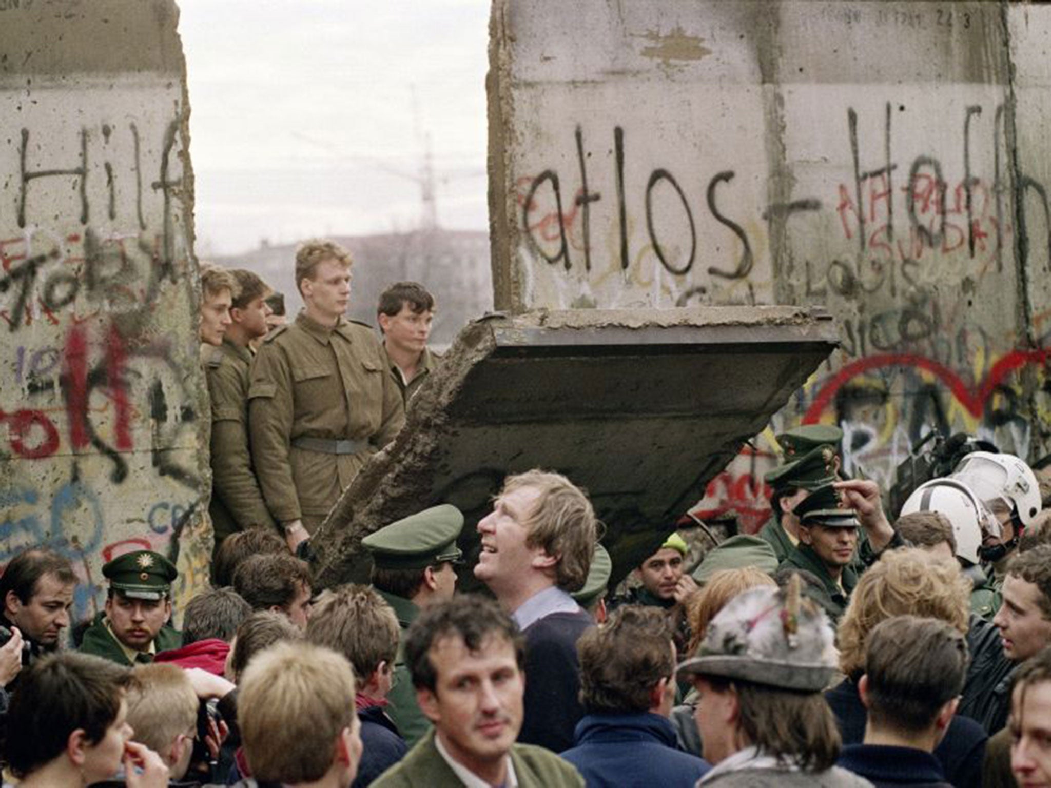 Police from both sides stand idly by as the Berlin Wall is breached for the first time between East and West, at the Sandkrug Bridge crossing-point on Invaliden Strasse, in November 1989