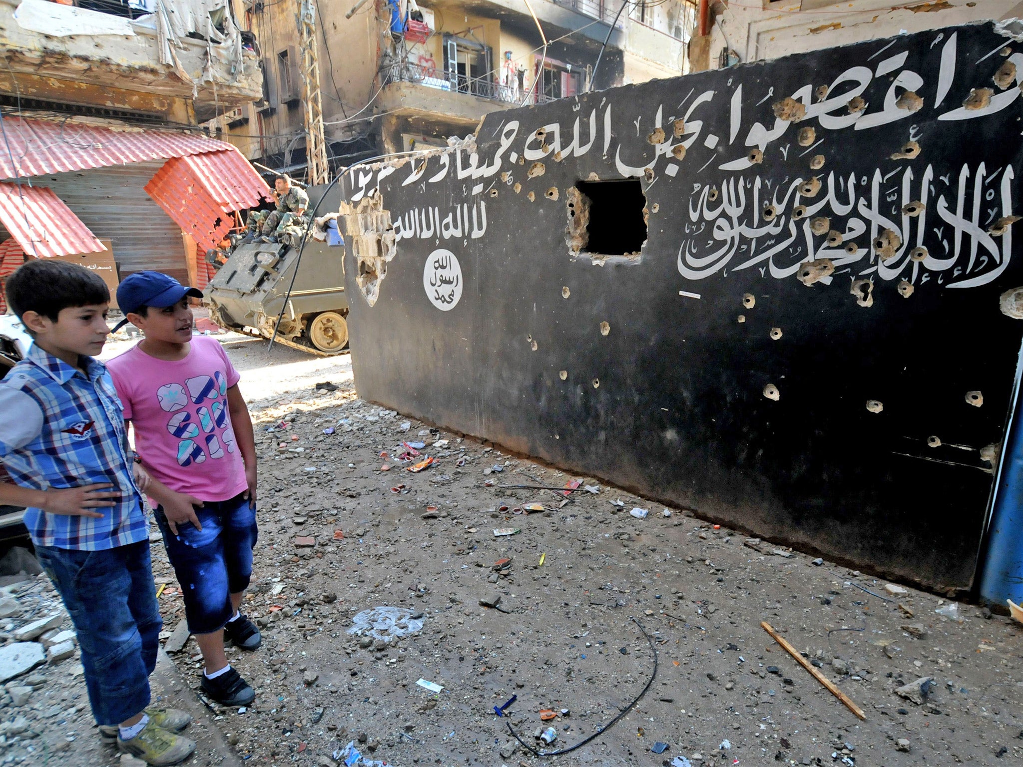 Lebanese boys look at a bullet-riddled mural of bearing Islamic texts on a wall in Tripoli's Bab al-Tabbaneh Sunni neighbourhood (Getty)