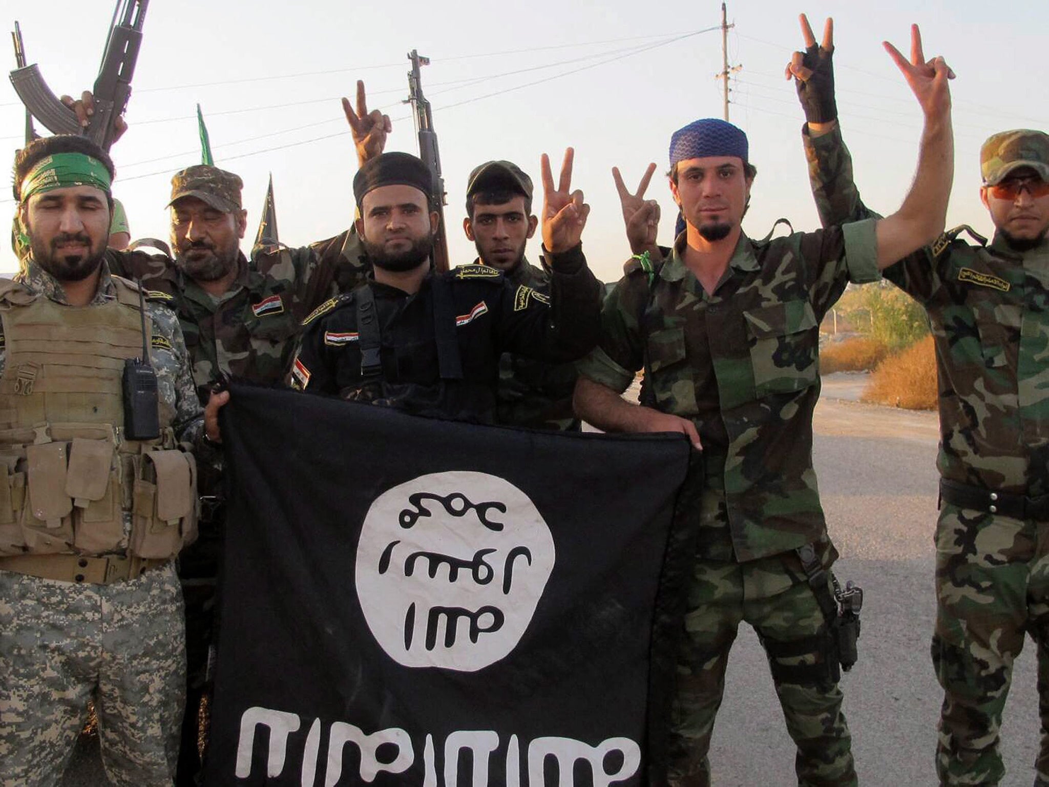 Members of the Iraqi Shiite militia, Kataib Hezbollah (Hezbollah Brigades) holding a flag belonging to Isis
