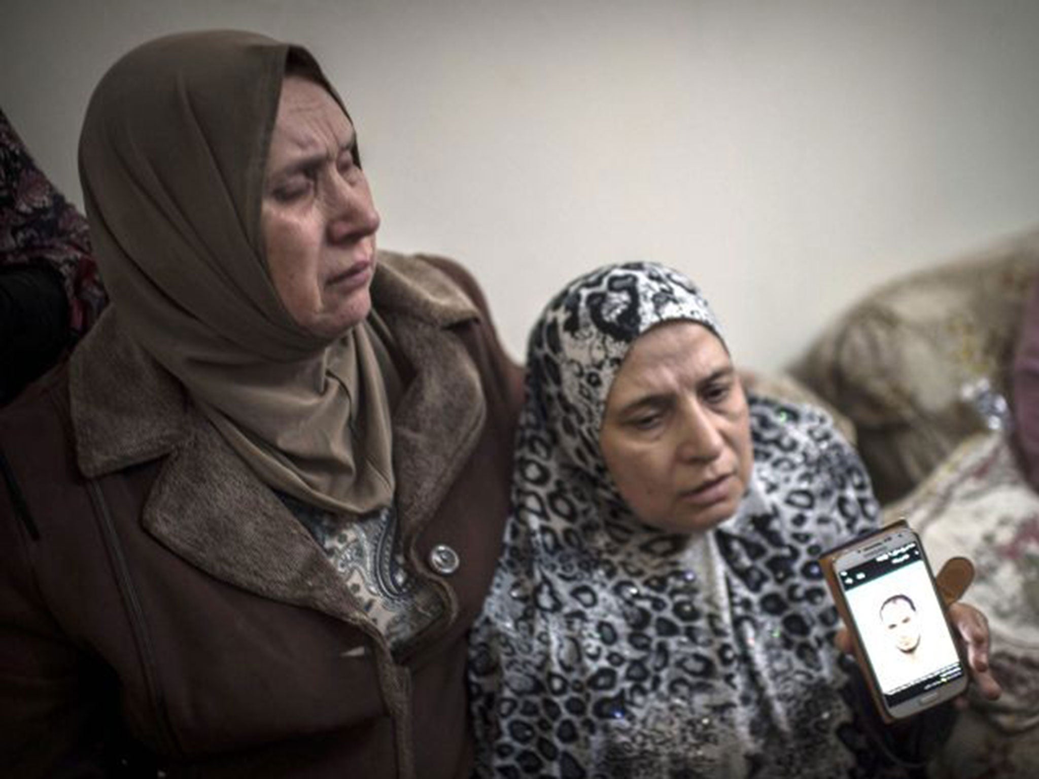 The familyof Moataz Hijazi hold a phone with an image as they mourn on October 30