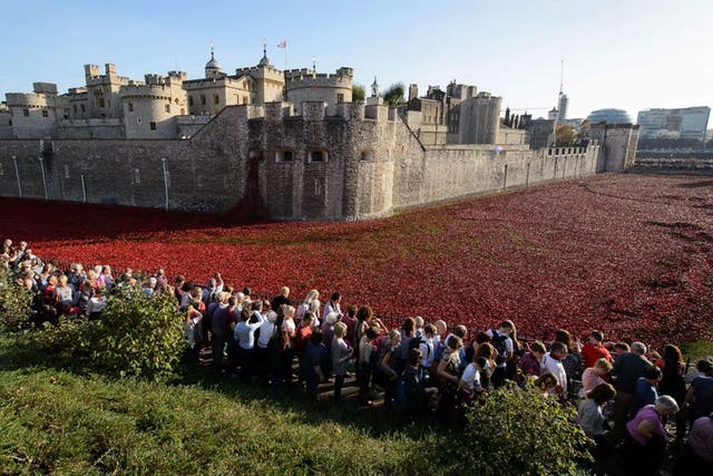 Visitors view the "Blood Swept Lands and Seas of Red" installation by ceramic artist Paul Cummins and theatre stage designer Tom Piper, marking the centenary of the outbreak of the First World War, in the moat area of the Tower of London in central London