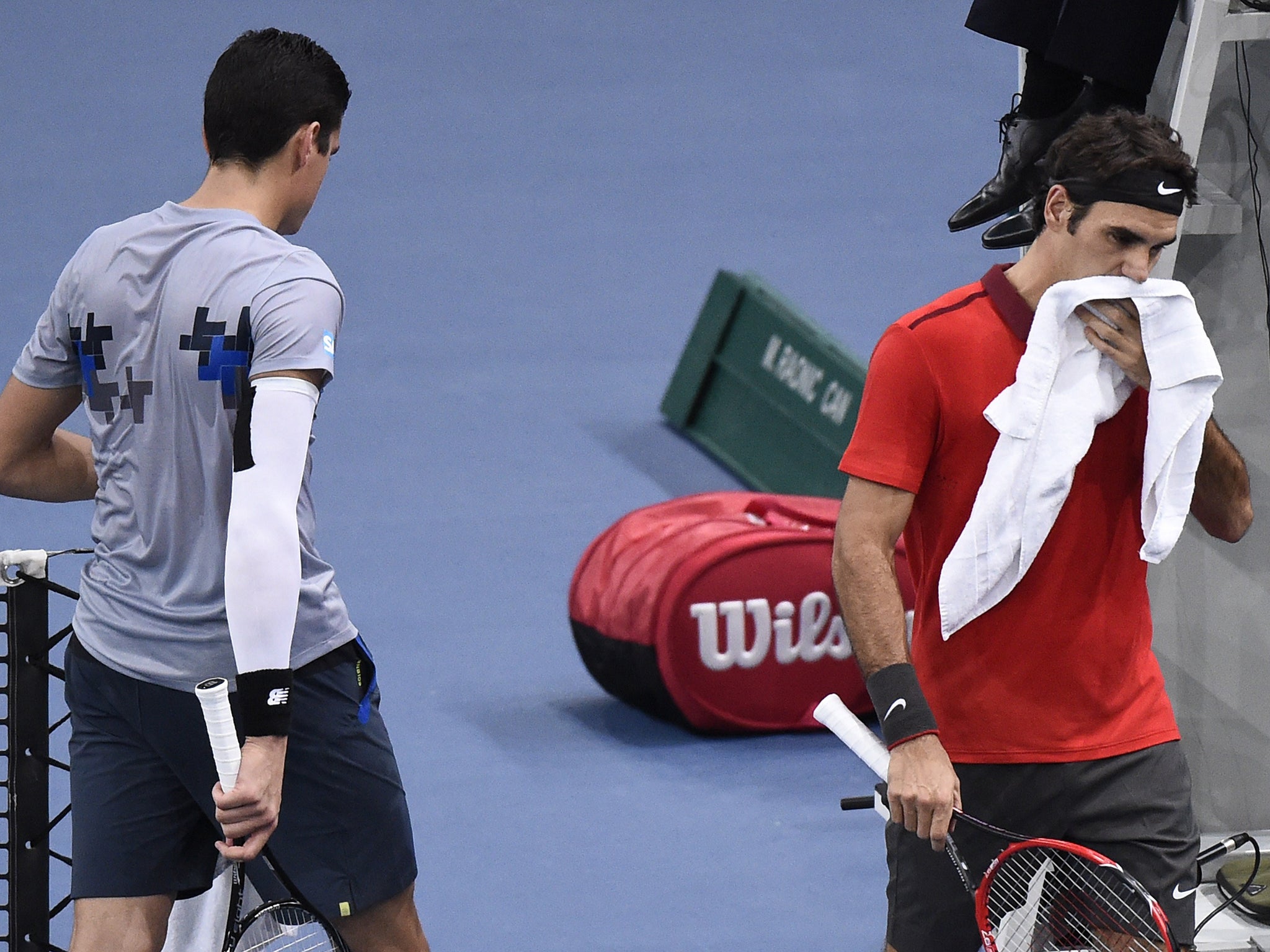 Switzerland's Roger Federer (R) walks to his seat after loosing the first set against Canada's Milos Raonic