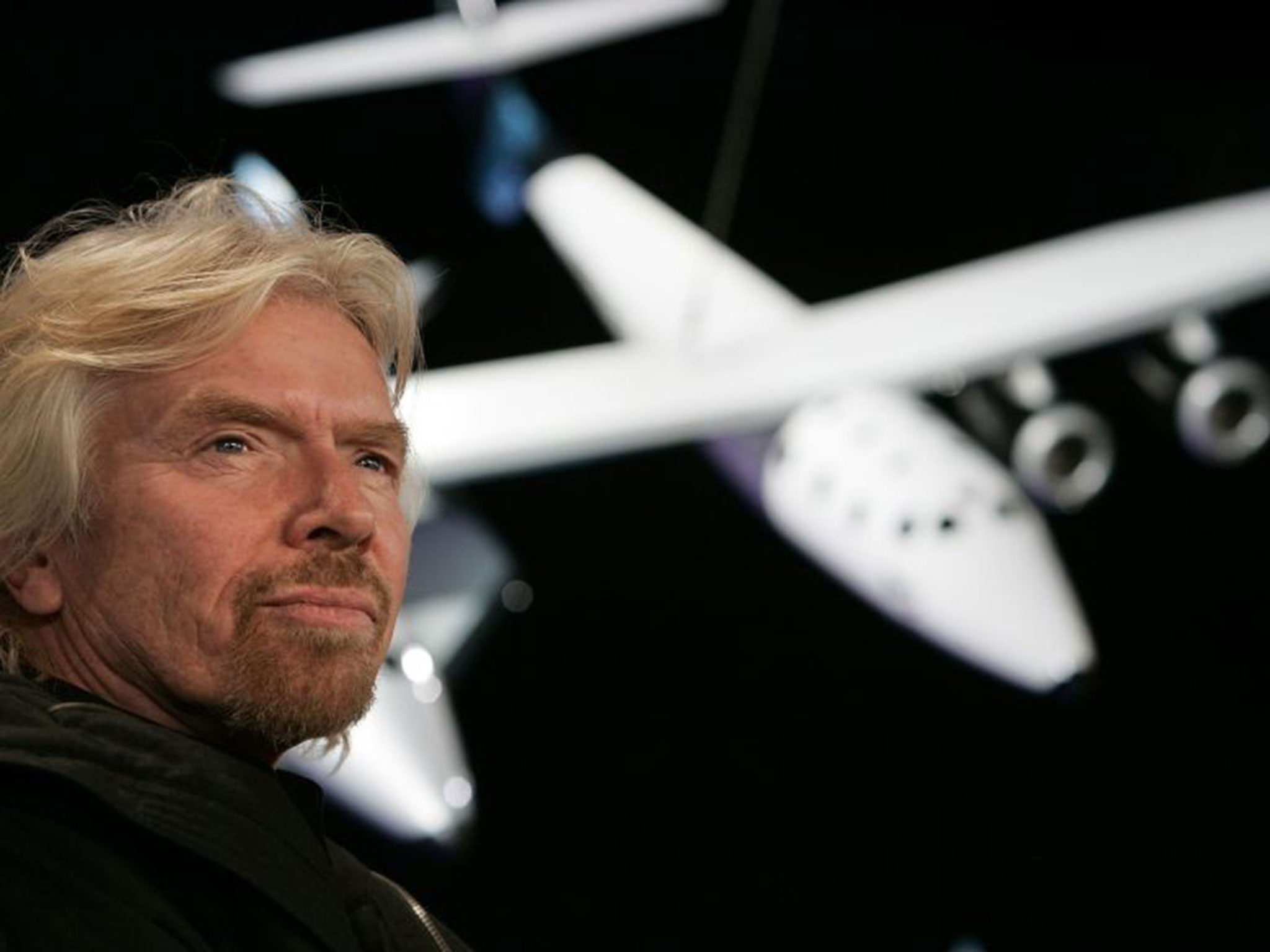 Sir Richard Branson, founder of Virgin Galactic, with a scale model of the Spaceship Two attached to the White Knight carrier aircraft in this January 2008 photograph