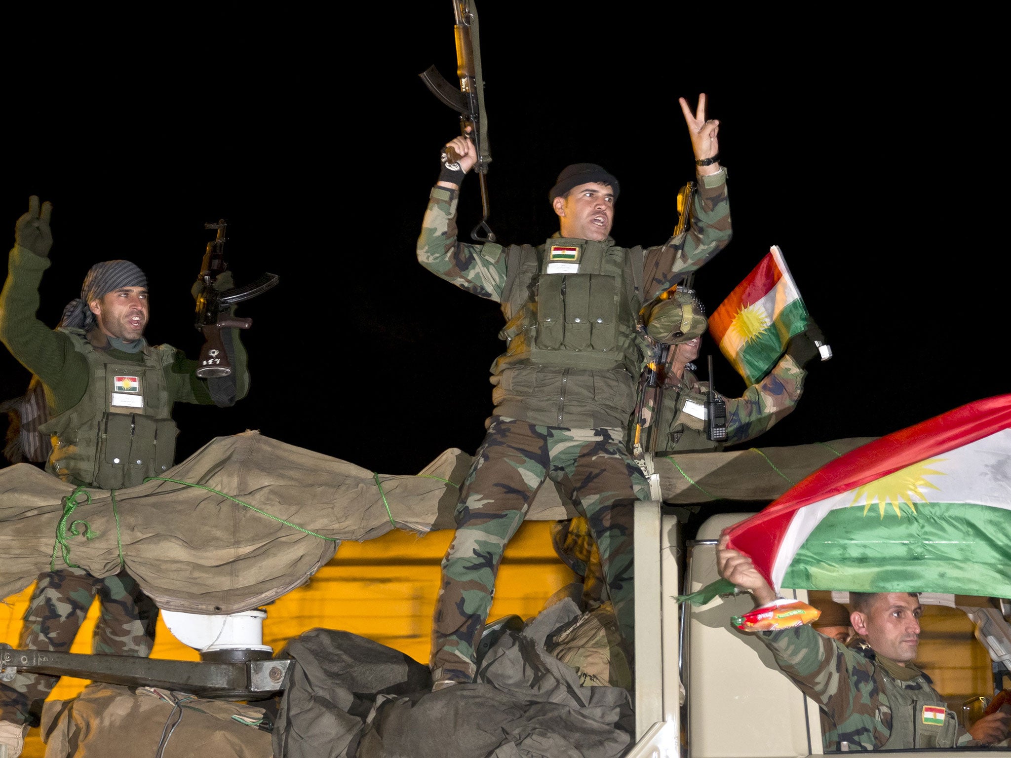 Iraqi Kurdish peshmerga fighters cheer as they leave the outskirts of Suruc, Turkey, towards the Turkey-Syria border, on the way to the Syrian city of Kobani