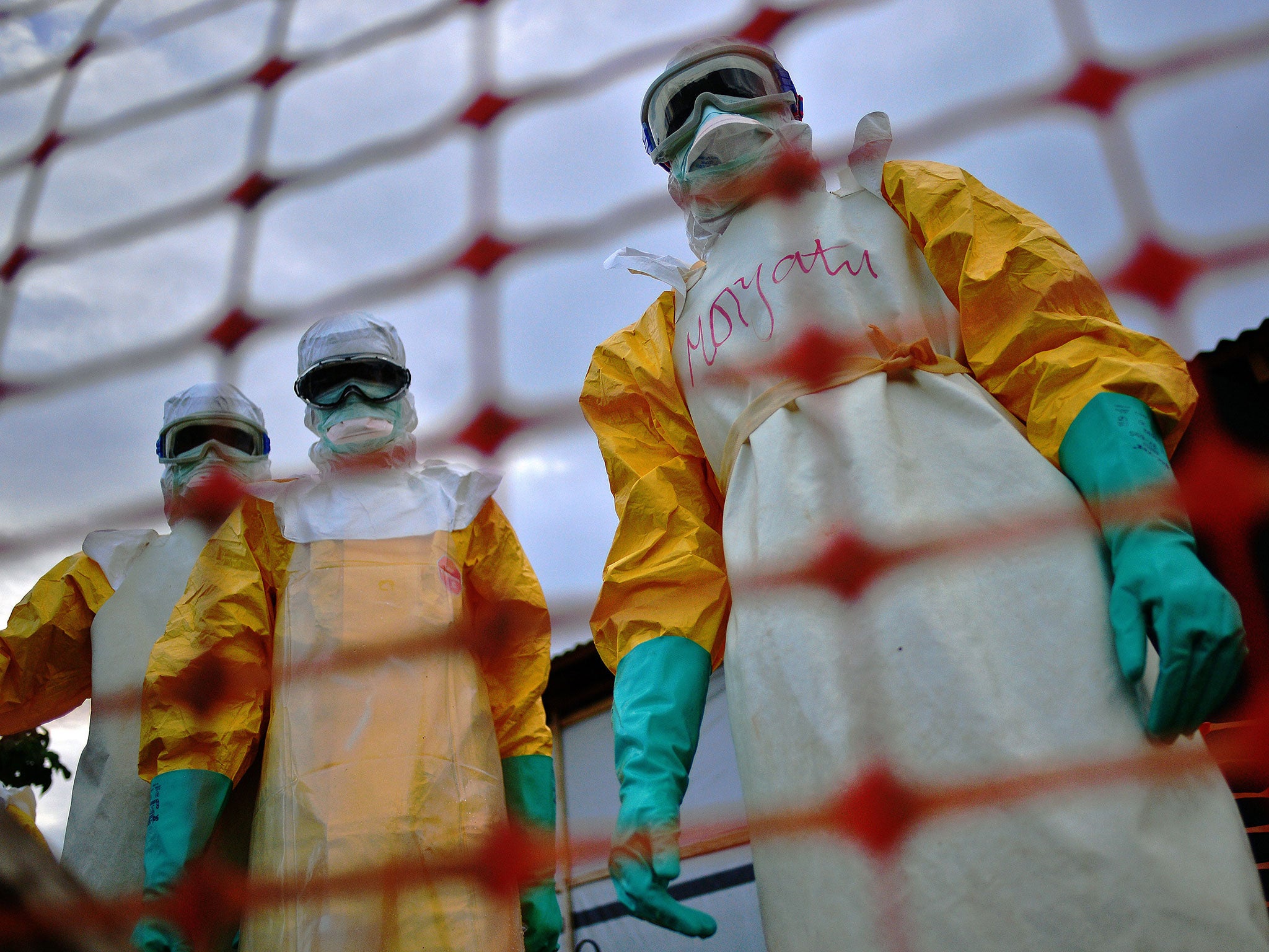 Médecins Sans Frontières medical staff wearing protective clothing treat the body of an Ebola victim