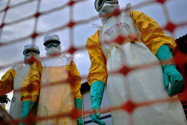 Médecins Sans Frontières medical staff wearing protective clothing treat the body of an Ebola victim