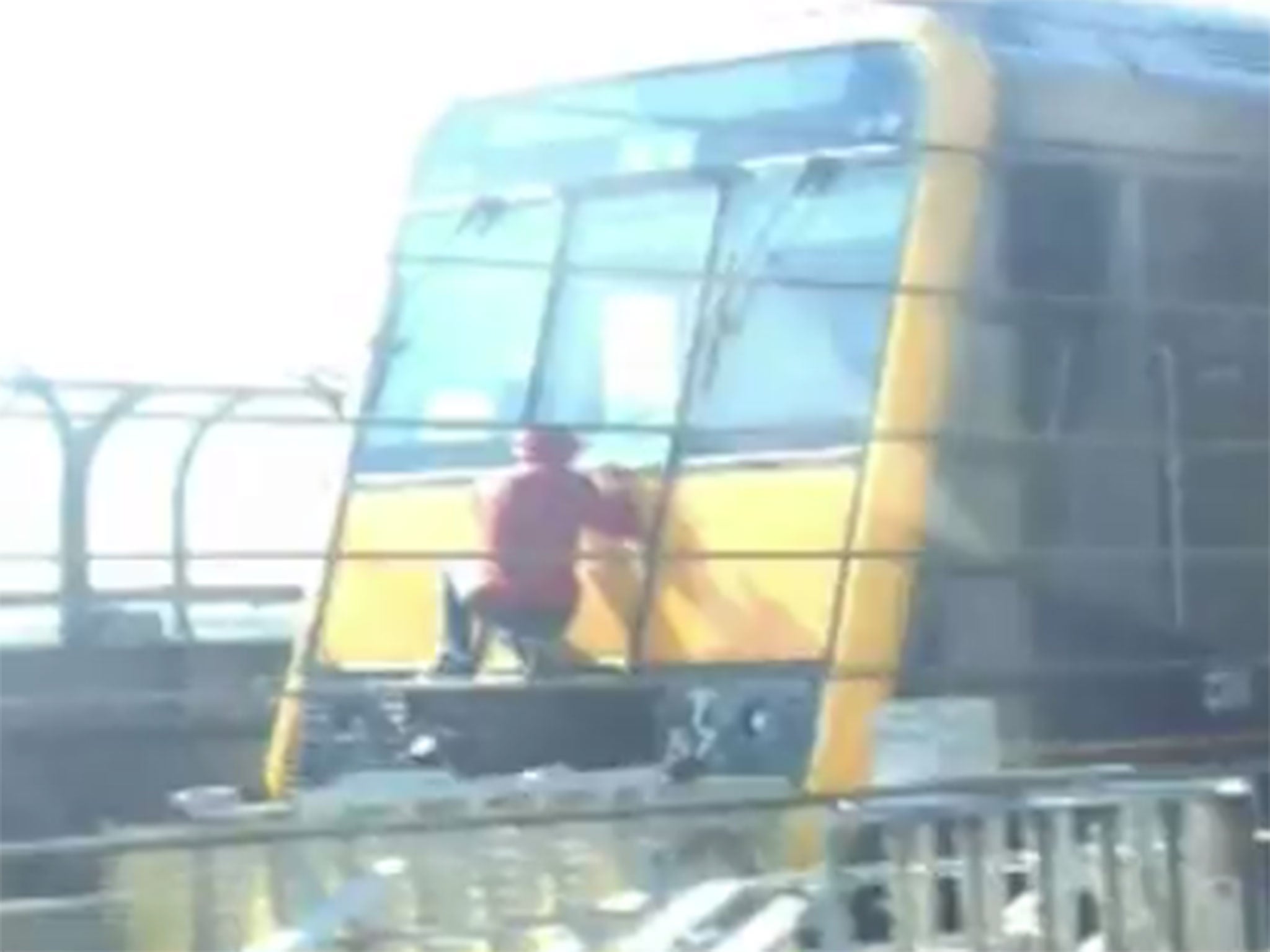 The 15-year-old was caught on camera holding onto the safety door at the back of the train by cameras