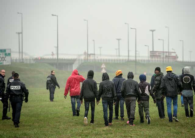 Police officers attempt to stop illegal migrants from jumping onto trucks headed for Britain in the northeastern French port of Calais on October 29, 2014