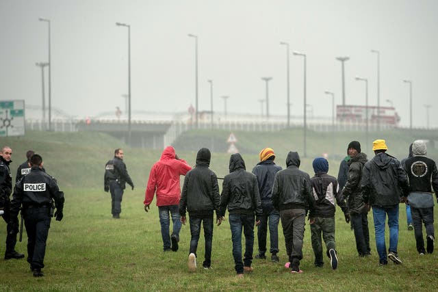 Police officers attempt to stop illegal migrants from jumping onto trucks headed for Britain in the northeastern French port of Calais on October 29, 2014