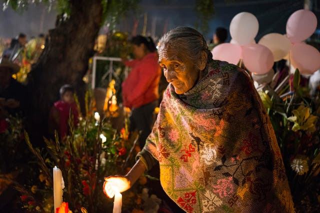 A woman lights a candle as she visits graves on the Day of the Dead festival in San Andre de Mixquic 