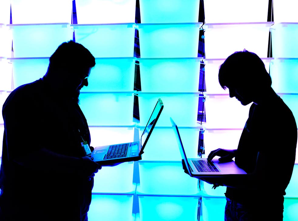 Participant hold their laptops in front of an illuminated wall at the annual Chaos Computer Club