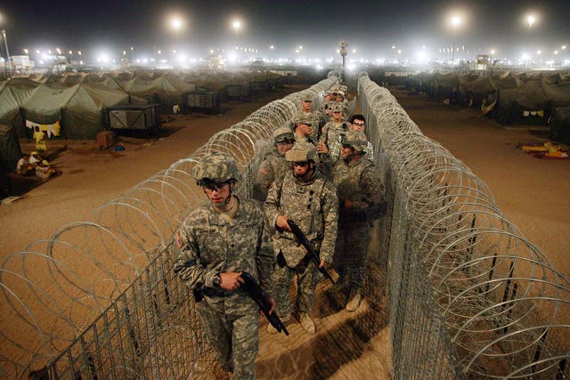 US Army soldiers carry shot guns as they walk along a corridor separating what they deem to be the most extreme and dangerous detainees held inside the Camp Bucca detention center located near the Kuwait-Iraq border