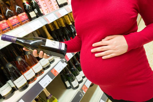 A pregnant woman buys wine at a supermarket