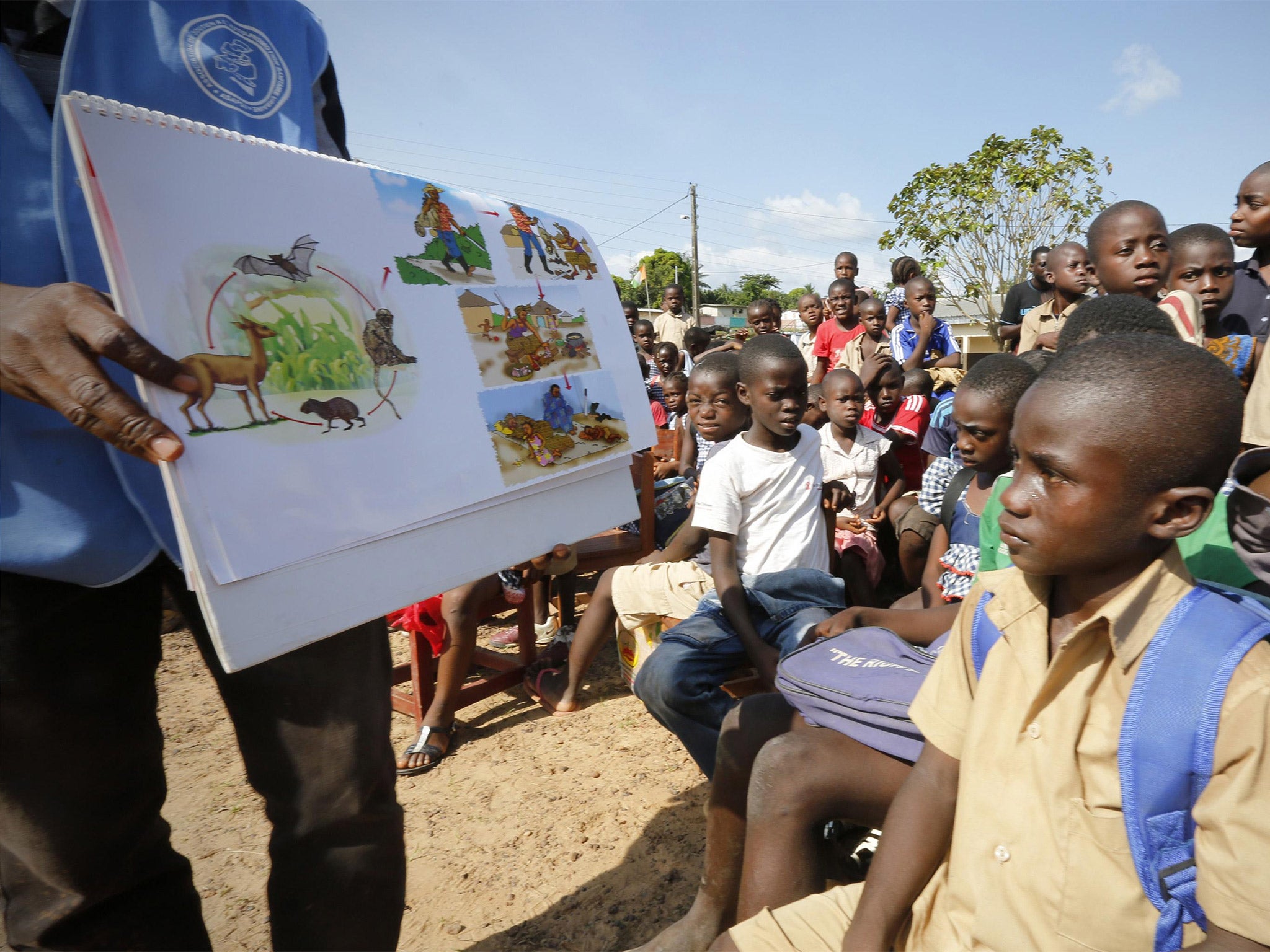 A man shows a picture chart regarding the Ebola virus to students during a UNICEF Ebola awareness drive in Toulepleu, at the border of Liberia, western Ivory Coast