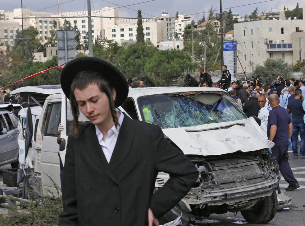 An ultra-orthodox Jew passes the car used in the attack; the driver was shot dead by police