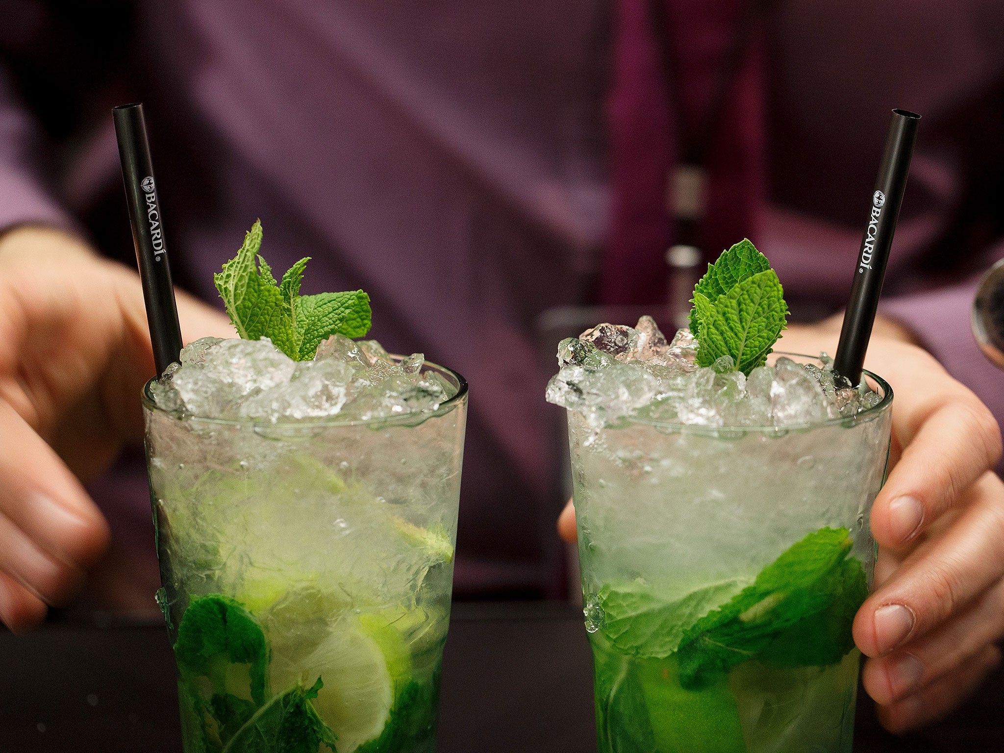 A bartender serves two Mojito cocktails