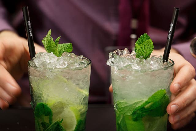 A bartender serves two Mojito cocktails 