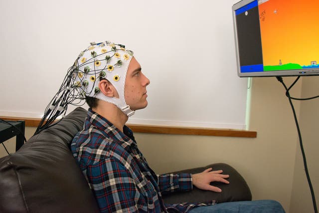 Student Darby Losey thinks about firing a cannon at various points throughout a computer game, whilst an an electroencephalography machine conveys his brain's signals directly to the brain of the receiver