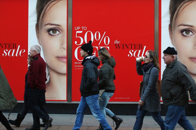 Shoppers walk past a sales sign on Oxford Street 