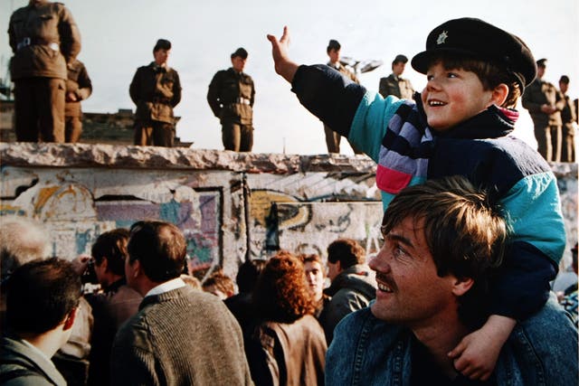 A boy waves to soldiers on the Berlin Wall in front of the Brandenburg Gate. (Photo by John Tlumacki/The Boston Globe via Getty Images)