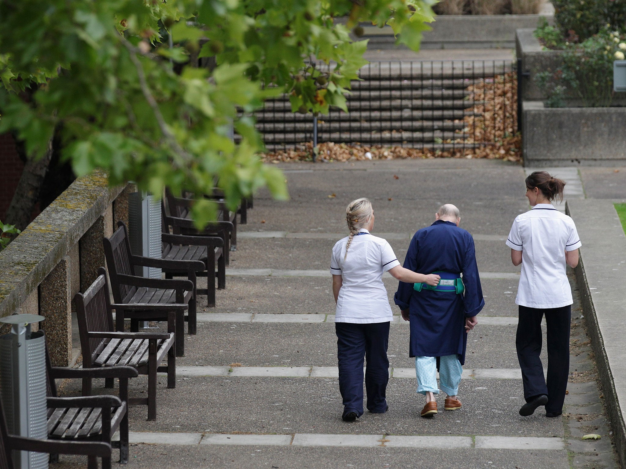 Two NHS staff walk with an elderly patient outside St Thomas' Hospital on October 13, 2011 in London, England.