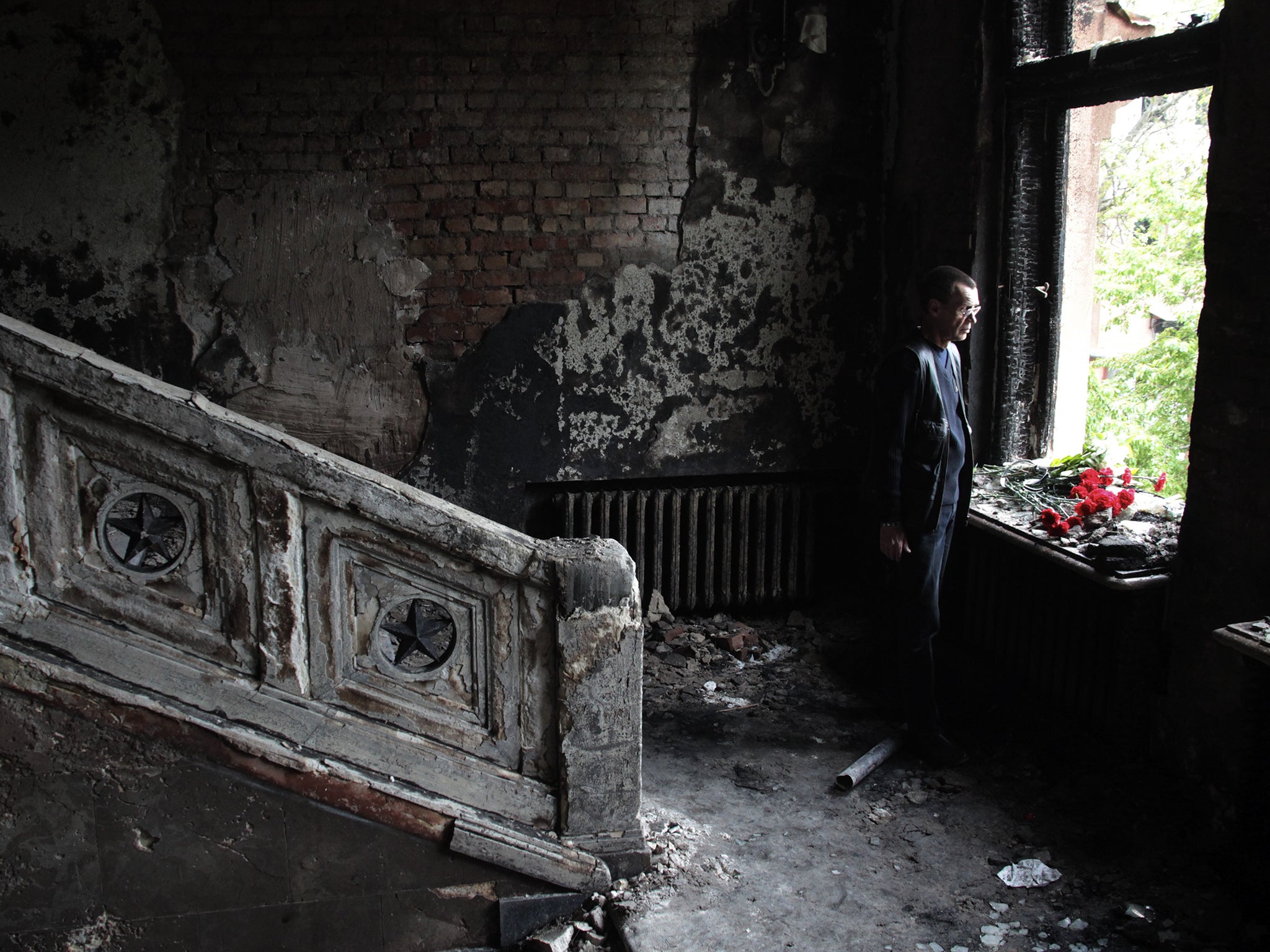 A man lays flowers inside the burnt trade union building in Odessa, Ukraine, where more than 50 people died following a series of riots