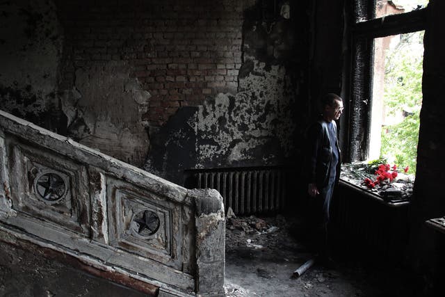 A man lays flowers inside the burnt trade union building in Odessa, Ukraine, where more than 50 people died following a series of riots