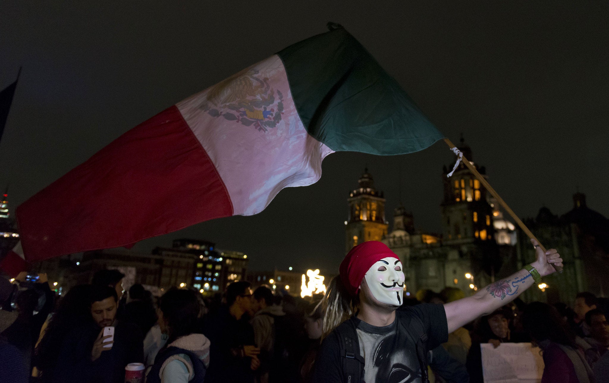 A demostrator waves a Mexican flag at the main entrance of the Mexican National Palace