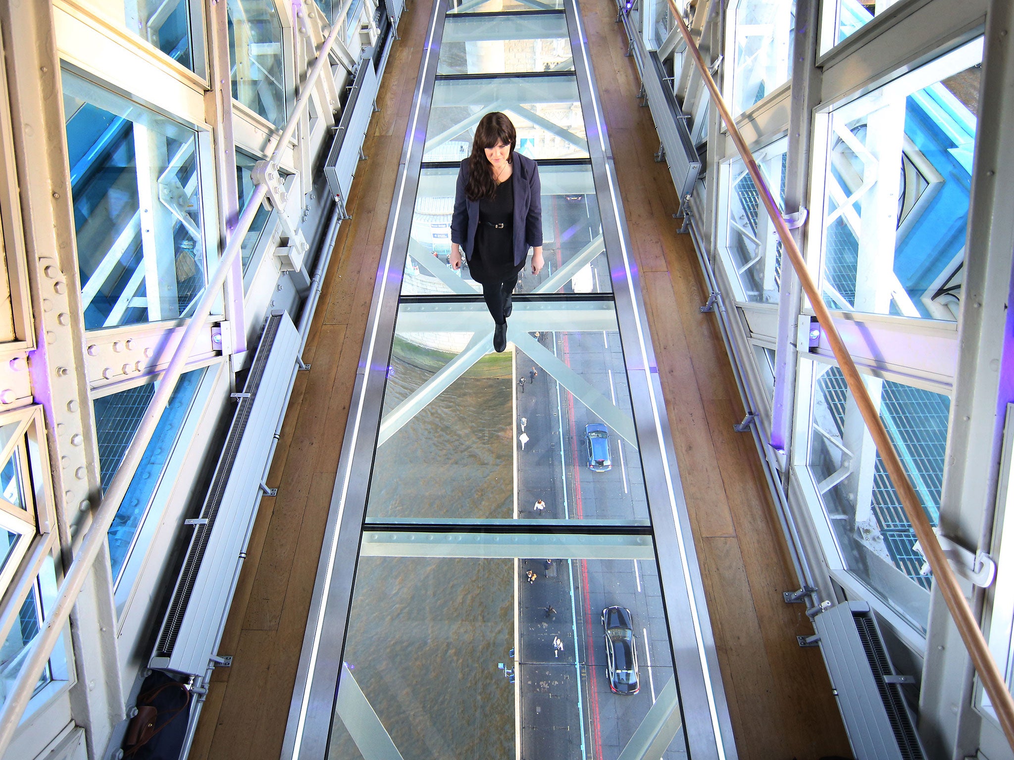 A visitor crosses Tower Bridge's new glass walkway on November 10, 2014 in London, England. Unveiled today the glass floor panels along the bridge's high-level walkways weigh 300 kgs each, cost £1m and will give visitors a new view over the historic bridg