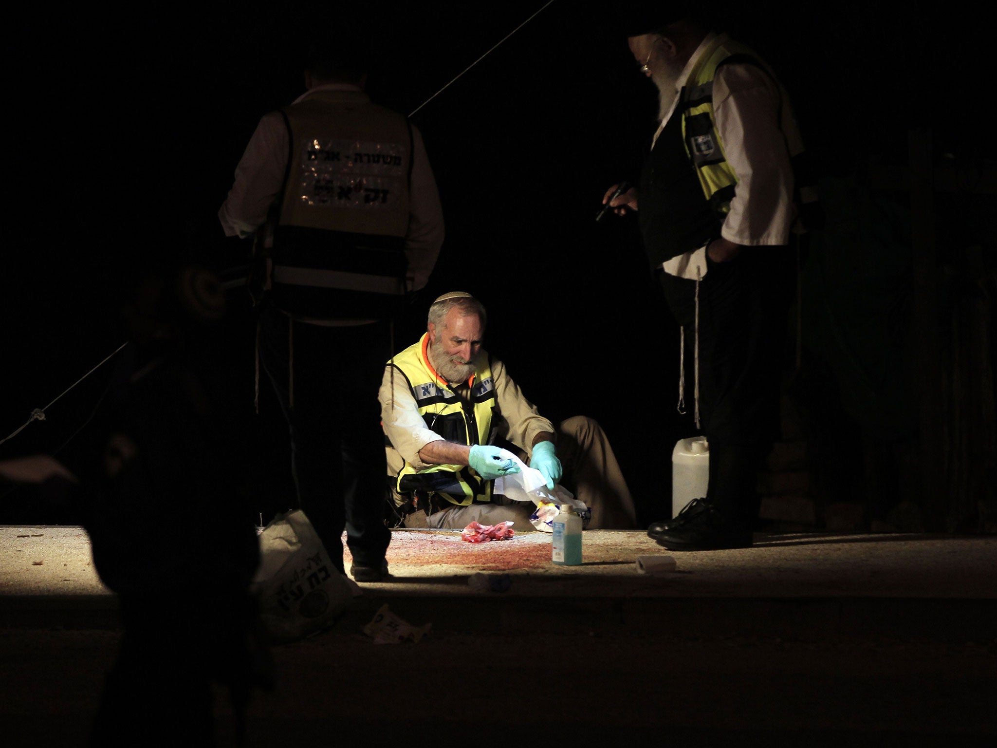 Israeli emergency services volunteers clean the site where a Palestinian man stabbed three Israelis outside the Alon Shvut settlement in the West Bank