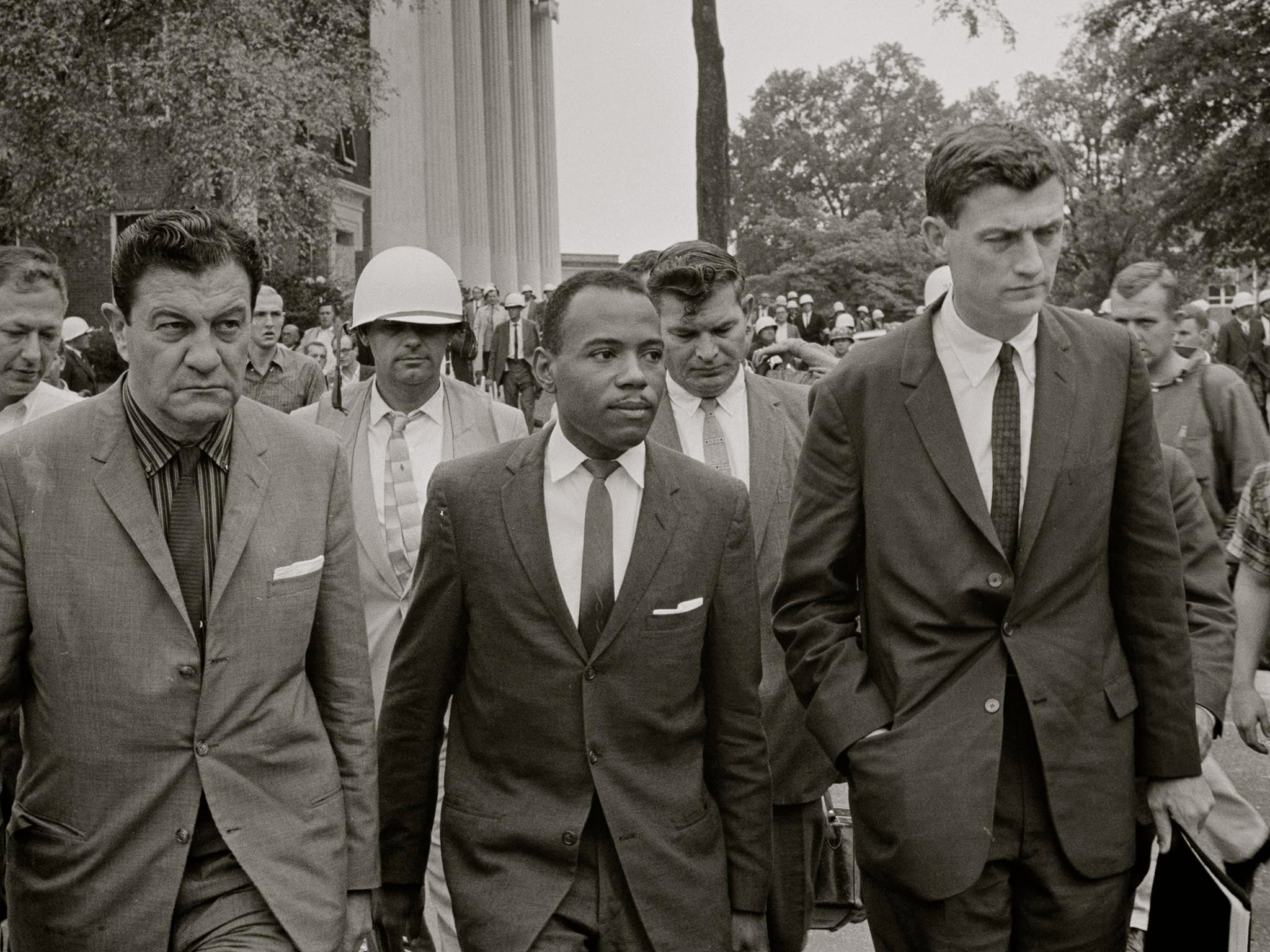 James Meredith walking to class accompanied by U.S. marshals and lawyer John Doar (right).