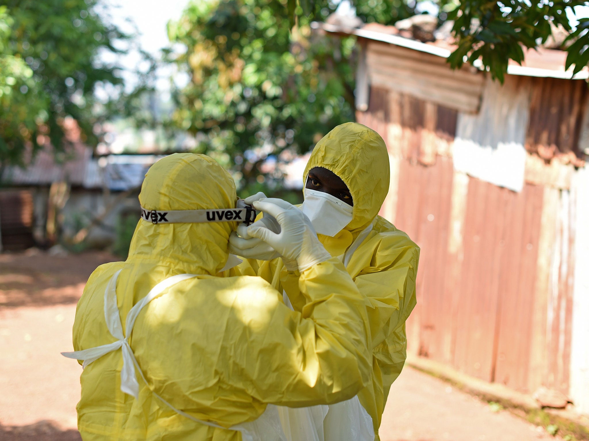 Health workers from Sierra Leone's Red Cross Society Burial Team 7 prepare to remove a body from a house in Freetown on November 12