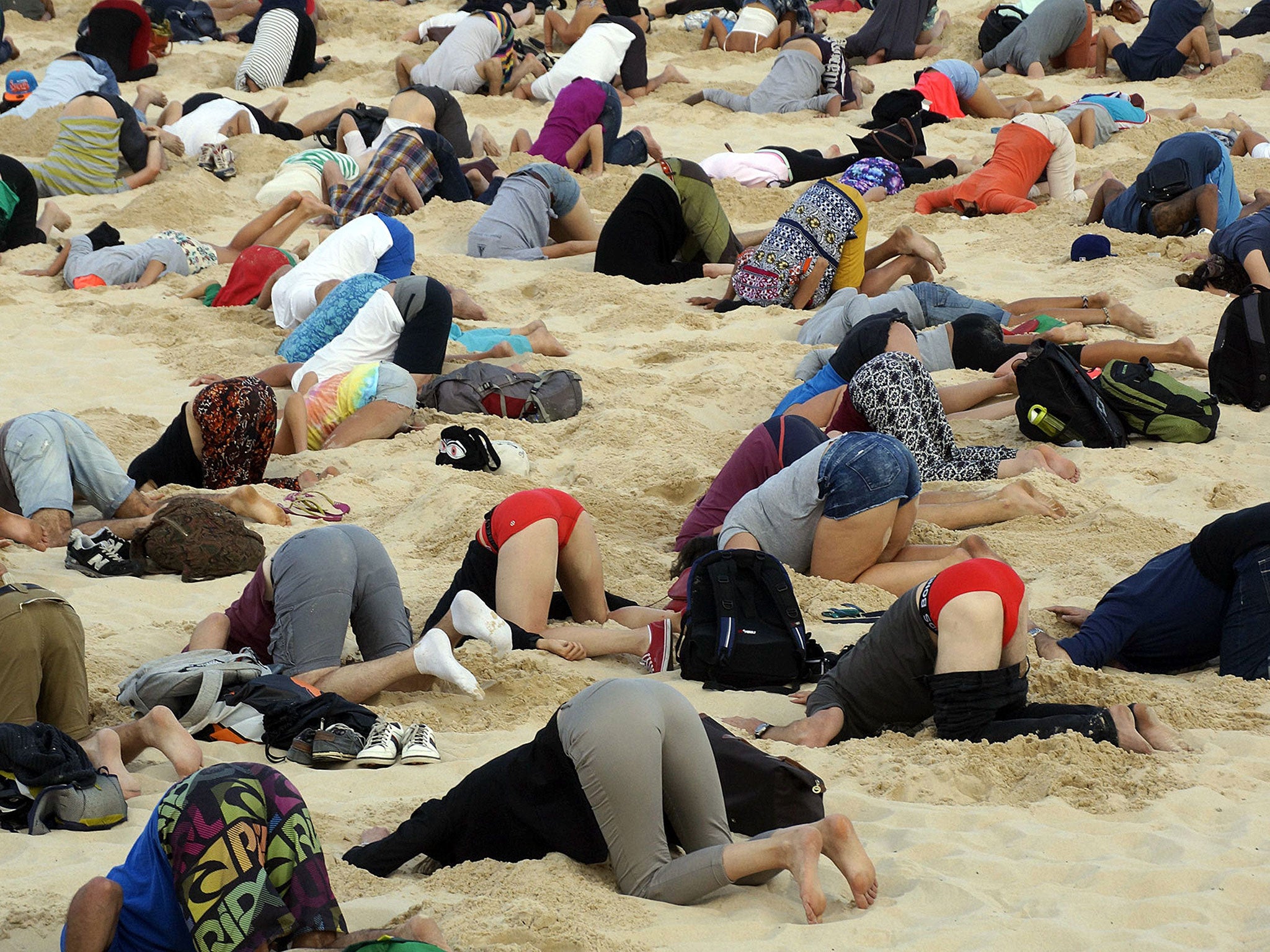 Australians bury their heads in the sands of Bondi Beach to send a message to Prime Minister Tony Abbott about the dangers of climate change