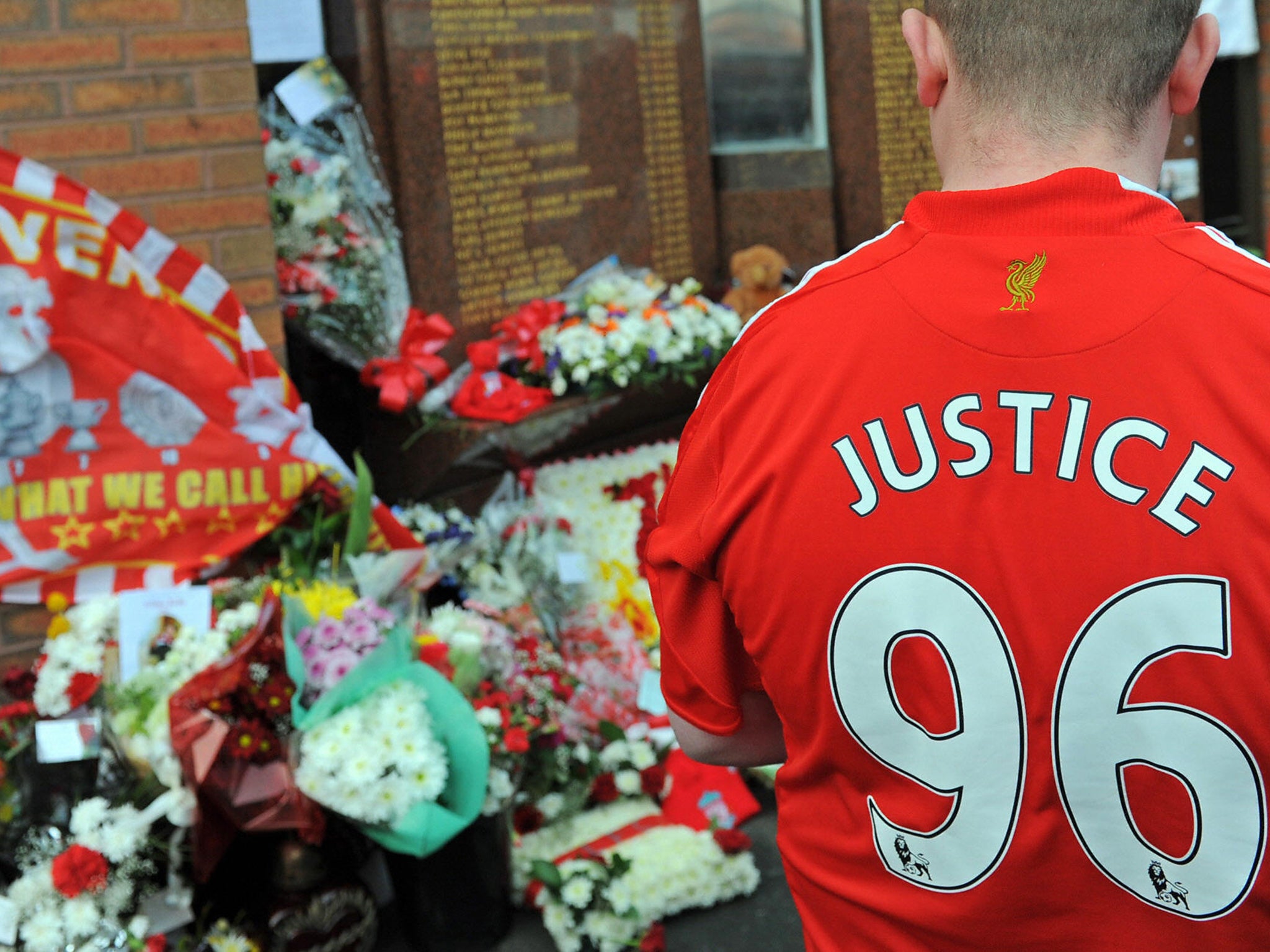 A Liverpool football club supporter looks at floral tributes and memorabilia to Hillsborough