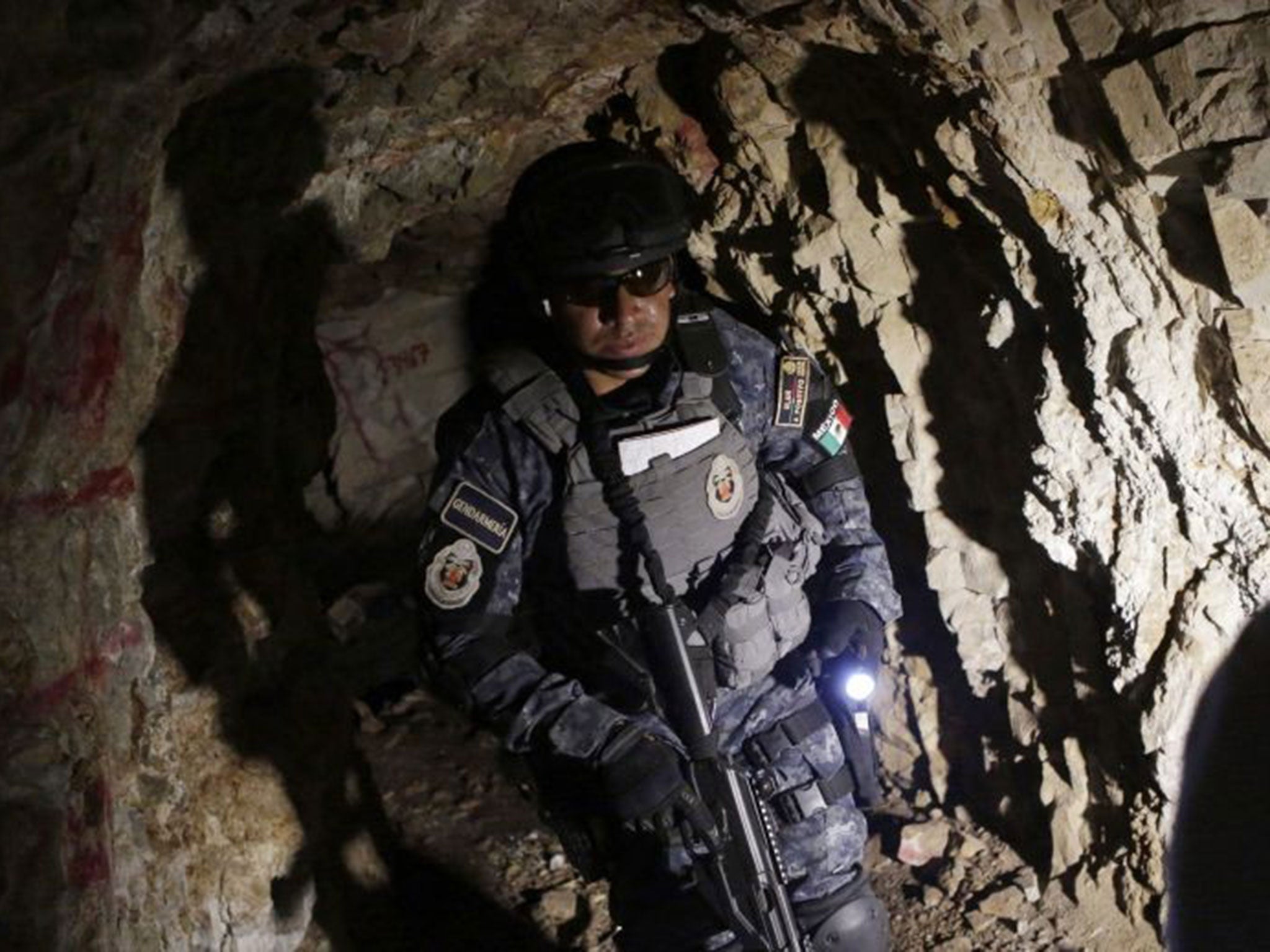 A federal police officer searches inside a cave for the 43 missing trainee teachers