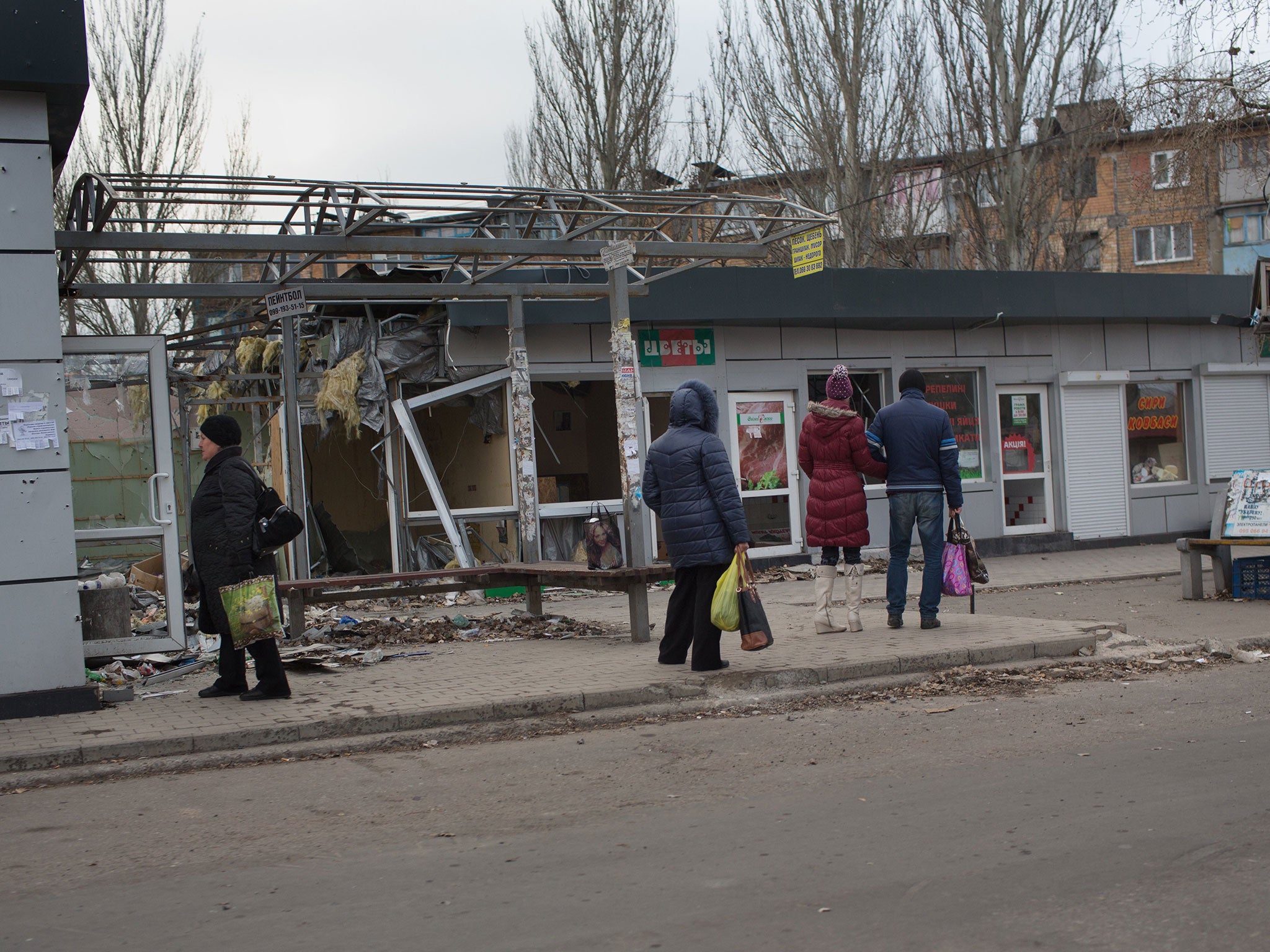 People watch a shop damaged by shells at Oktyabrskiy district in the city of Donetsk as artillery fire continues to rock the eastern Ukraine's pro-Russian rebel bastion of Donetsk