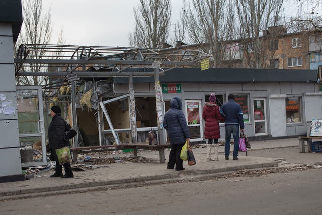 People watch a shop damaged by shells at Oktyabrskiy district in the city of Donetsk as artillery fire continues to rock the eastern Ukraine's pro-Russian rebel bastion of Donetsk