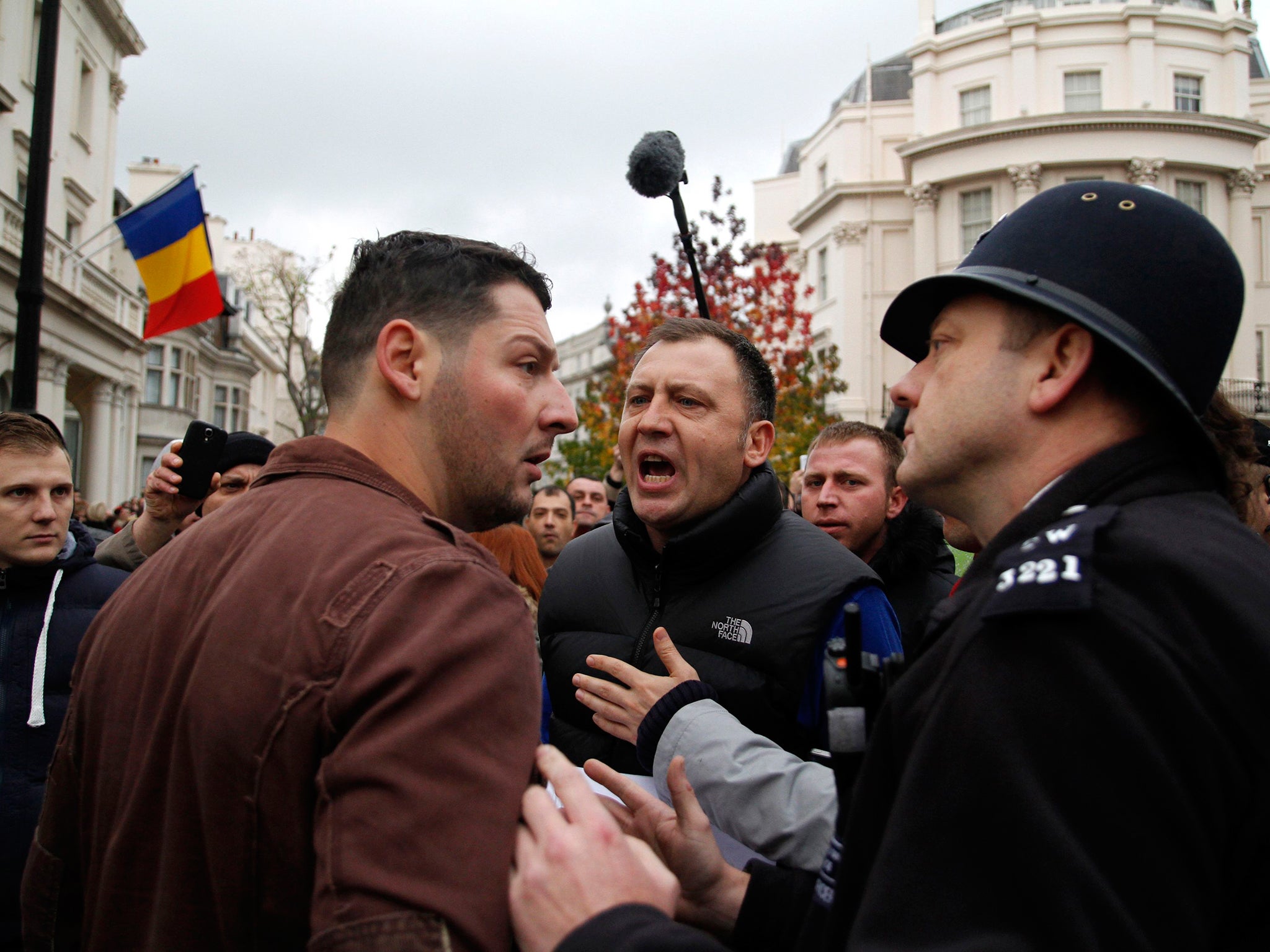 A policeman intervenes between two Romanians arguing as they wait in line to enter a polling station at the Romanian embassy in London