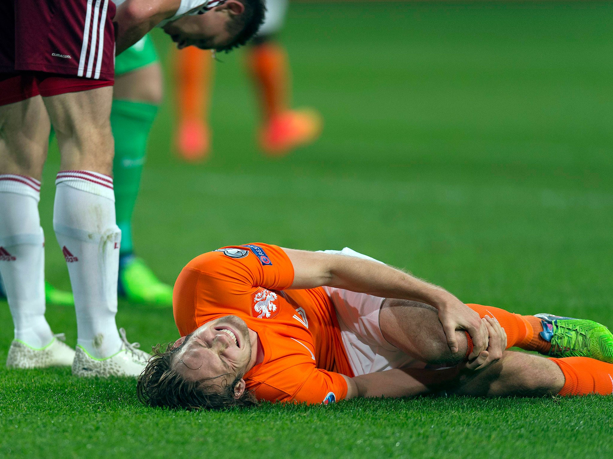 Daley Blind of the Netherlands lies injured after a challenge with Latvia's Eduards Viskanovs