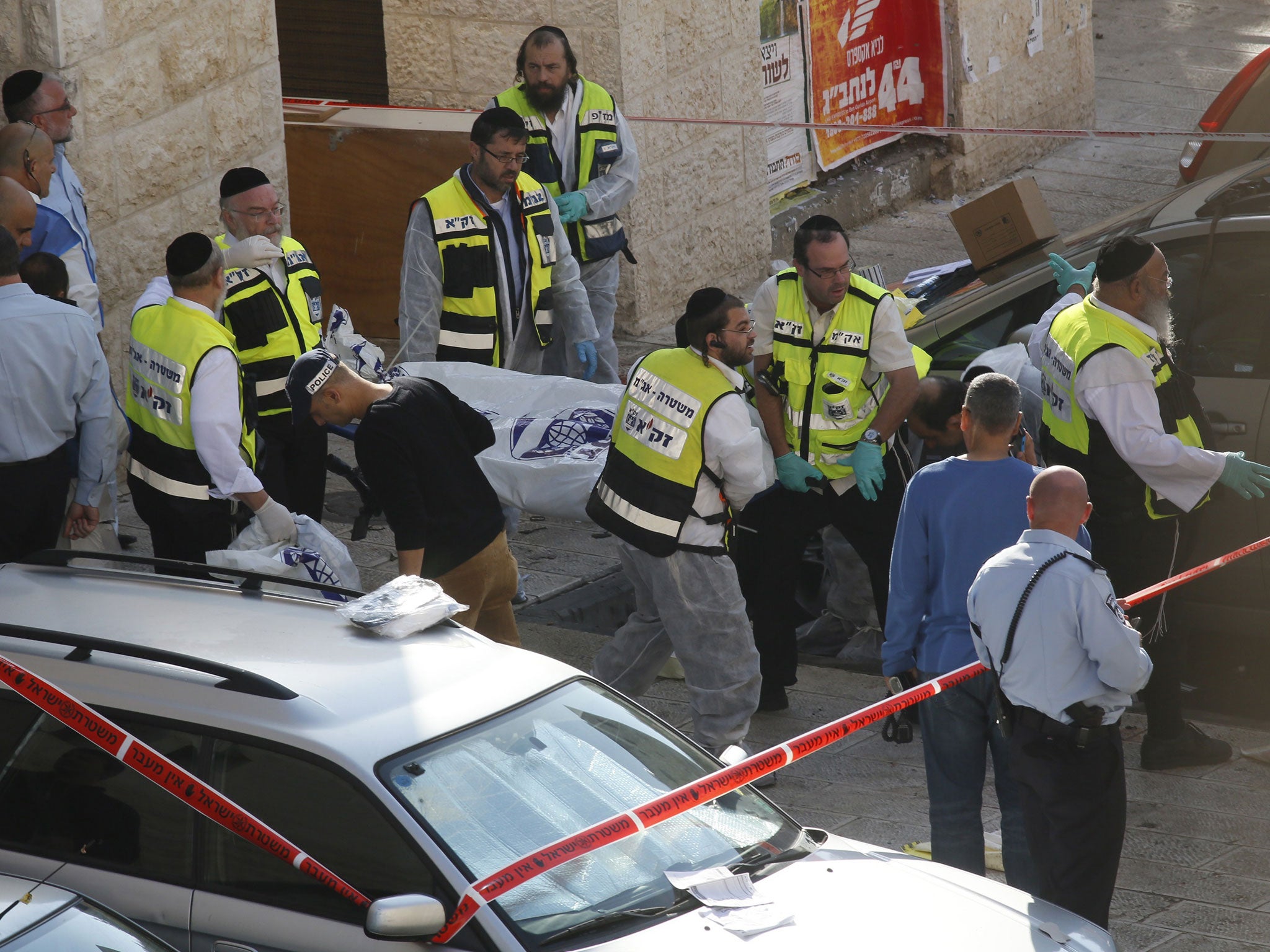 Israeli Zaka emergency services volunteers carry the body of an assailant who was shot dead while attacking a synagogue